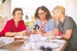 © Krakenimages.com - Meeting of middle age women having lunch and drinking coffee. Mature friends smiling happy using smartphone at home on a sunny day