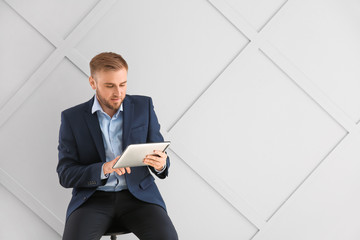 Wall Mural - Portrait of handsome businessman with tablet computer on light background