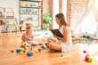 © Krakenimages.com - Beautiful psycologist and blond toddler girl doing therapy building tower using plastic blocks at kindergarten