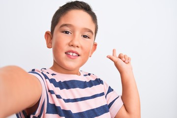 Beautiful kid boy wearing casual striped t-shirt make selfie over isolated white background very happy pointing with hand and finger to the side