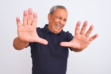 Sticker - Senior grey-haired man wearing black casual polo standing over isolated white background afraid and terrified with fear expression stop gesture with hands, shouting in shock. Panic concept.