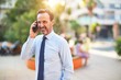 © Krakenimages.com - Middle age handsome businessman standing on the street talking on the smartphone smiling