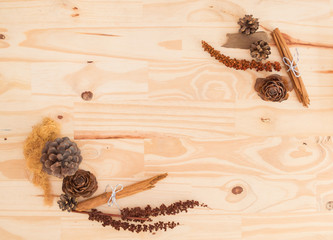 Autumn natural decorations frame with copy space for text isolated on a rustic wooden table background: pine cones, cinnamon sticks, leaves and branches / For weddings, fall, winter and holidays