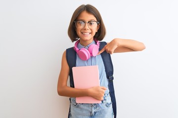 Sticker - Student child girl wearing backpack glasses book headphones over isolated white background with surprise face pointing finger to himself