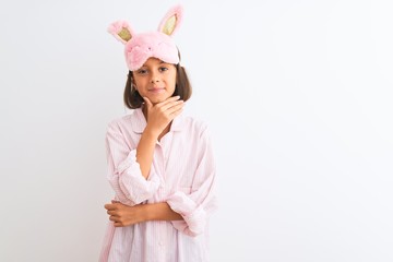 Sticker - Beautiful child girl wearing sleep mask and pajama standing over isolated white background looking confident at the camera with smile with crossed arms and hand raised on chin. Thinking positive.