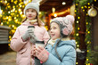 © MNStudio - Two adorable sisters drinking hot chocolate on traditional Christmas fair in Riga, Latvia. Children enjoying sweets, candies and gingerbread on Xmas market.