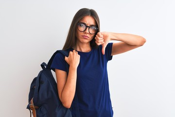 Wall Mural - Young beautiful student woman wearing backpack and glasses over isolated white background with angry face, negative sign showing dislike with thumbs down, rejection concept