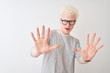 © Krakenimages.com - Young albino blond man wearing striped t-shirt and glasses over isolated white background afraid and terrified with fear expression stop gesture with hands, shouting in shock. Panic concept.