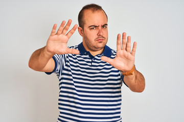 Young man wearing casual striped polo standing over isolated white background doing frame using hands palms and fingers, camera perspective