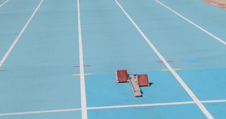 Wall Mural - Sprinter runner athlete running in starting blocks training sprinting start of sprint on blue running tracks at outdoor athletics track and field stadium. Sport and fitness man running sprinting.