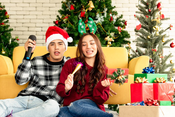 Young Asian couples sing a song celebrating Christmas party with happy in home. Copy Space.