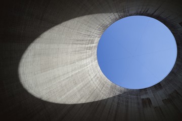 Wall Mural - Low angle shot from inside of a cooling tower with a blue sky in the background