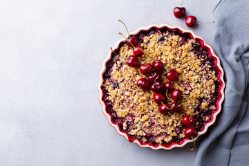 Cherry, red berry crumble in baking dish. Grey background. Top view. Copy space.