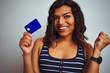 © Krakenimages.com - Transsexual transgender customer woman holding credit card over isolated white background screaming proud and celebrating victory and success very excited, cheering emotion