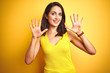 © Krakenimages.com - Young beautiful woman wearing t-shirt standing over yellow isolated background showing and pointing up with fingers number ten while smiling confident and happy.