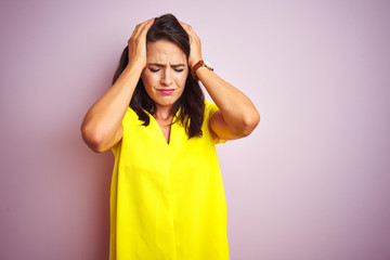 Wall Mural - Young beautiful woman wearing yellow t-shirt standing over pink isolated background suffering from headache desperate and stressed because pain and migraine. Hands on head.