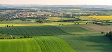 Breathtaking Aerial Shot Of Green Fields On Hills Next To Small Settlement
