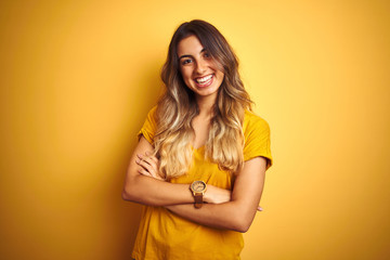 Sticker - Young beautiful woman wearing t-shirt over yellow isolated background happy face smiling with crossed arms looking at the camera. Positive person.