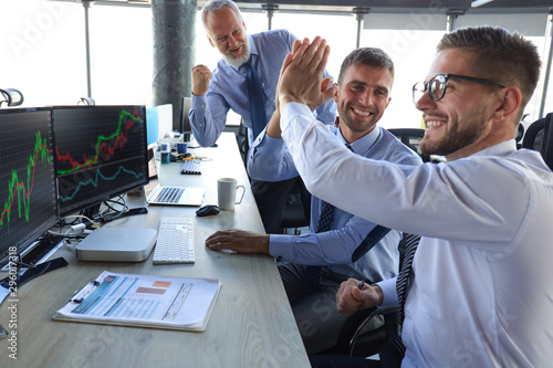 Cuadros en Lienzo Group of modern business men in formalwear smiling and gesturing while working in the office