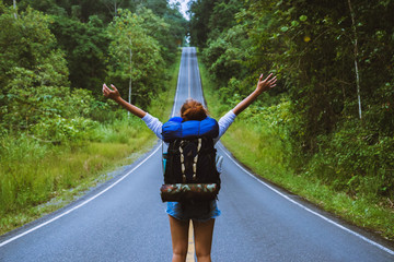 Freedom traveler woman standing with raised arms and enjoying a beautiful nature On a country road. woman with backpack travel In the countryside On a mountain.