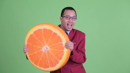 Wall Mural - Happy Asian businessman with eyeglasses holding orange pillow as healthy concept