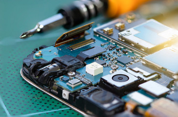 Closeup image of motherboard of mobile smart phone and screwdriver.