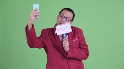 Wall Mural - Happy Asian businessman taking selfie with paper sign