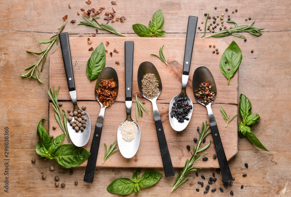 Spoons with different spices on wooden background