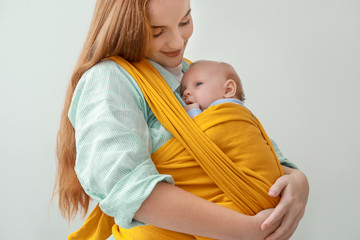 Poster - Young mother with little baby in sling on white background