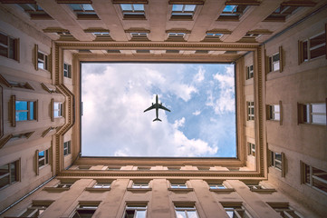 Wall Mural - Airplane traveling in the sky over the city buildings in downtown travel destination of Europe.