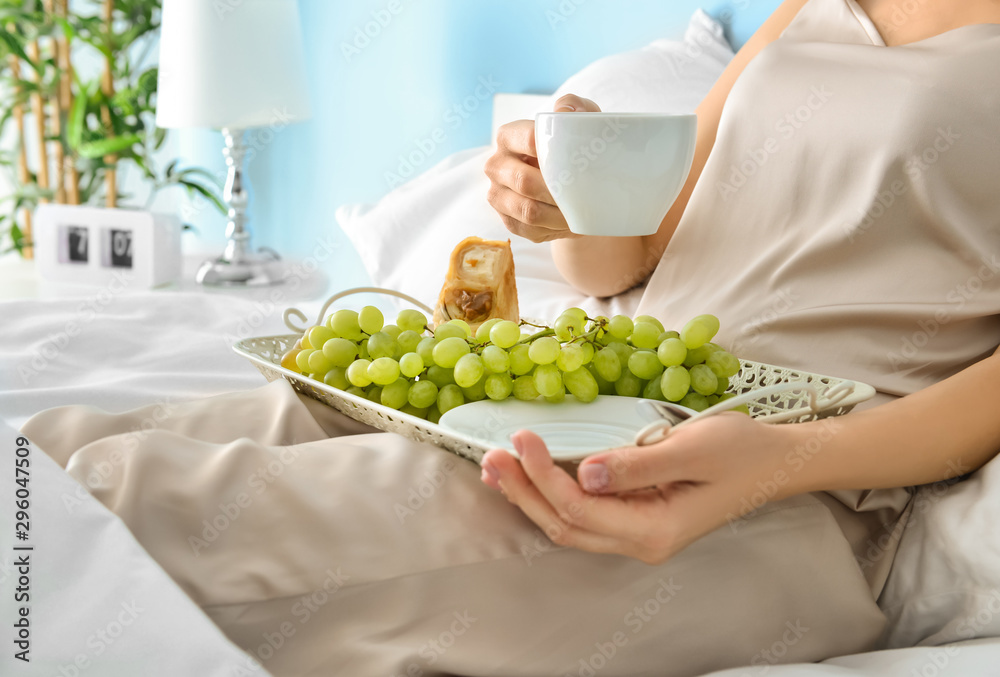 Young woman having tasty breakfast in bed
