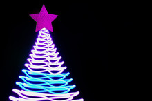 Christmas Tree In Neon Pink And Blue Freezelight Rays On Black. Creative Pattern With Space For Text And Holiday Wishes. Xmas Party Background.