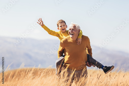 Fotomural Grandson piggyback with his grandfather in autumn.