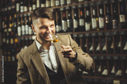 Fotomural Smiling sommelier in the wine cellar tasting whiskey.
