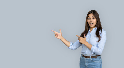 Wall Mural - Excited overjoyed indian girl shopper looking pointing fingers aside isolated on grey studio background show copy space, amazed young woman customer happy by shopping sale offer, banner