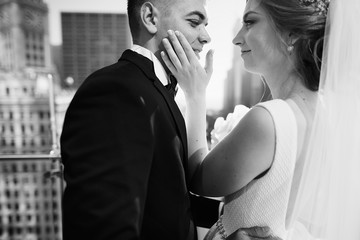 Wall Mural - Elegant bride in a white dress and veil. Handsome groom in a blue suit. Couple in a big town