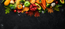Autumn Vegetables And Fruits On A Black Stone Background: Pumpkin, Tomatoes, Corn, Pomegranate, Persimmon, Apple. Top View. Free Copy Space.