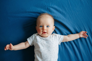 portrait of cute adorable smiling white caucasian baby girl boy with blue eyes four months old lying