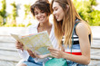 © Drobot Dean - Photo of two pretty tourist women holding paper map in green boulevard