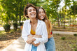 © Drobot Dean - Photo of two women hugging and laughing while walking in green park