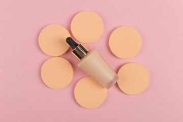 Wall Mural - Sponges, a beautiful blender for applying foundation or powder and a bottle of concealer. Flat lay on a pink background, copy space.