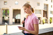 © mimagephotos - Side teen girl walking outside with mobile phone and bag