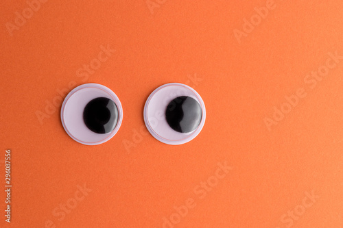 Fotomural Googly eyes on orange background. Minimal holiday concept.