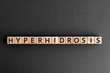 Hyperhidrosis - word from wooden blocks with letters, excessive sweating hyperhidrosis concept,  top view on grey background