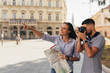 Leinwanddruck Bild - couple tourist in sightseeing in city using paper map and taking pictures with camera