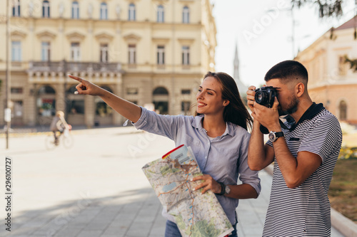 Fotomural couple tourist in sightseeing in city using paper map and taking pictures with c