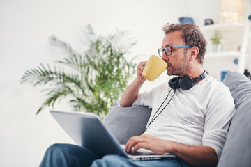 Wall Mural - Man listening to music and using laptop in the living room.