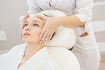 Unknown masseuse beautician doing a face massage to her client a beautiful young woman. Skin care concept