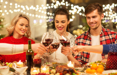 Sticker - holidays and celebration concept - happy friends having christmas dinner at home, drinking red wine and clinking glasses