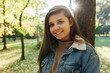 © Michał Magiera - Smiling young woman leaning against a tree in the park.